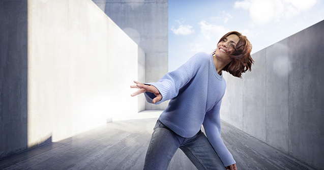 Frau schaut in Himmer und streckt Arm nach vorne